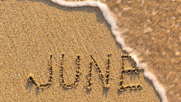 Inscription JUNE on a gentle beach sand with the soft wave (months of the year series)
